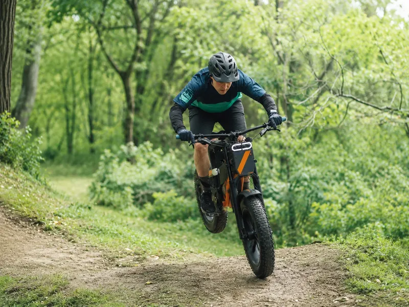 Rider jumping an electric mountain bike on a forest dirt trail