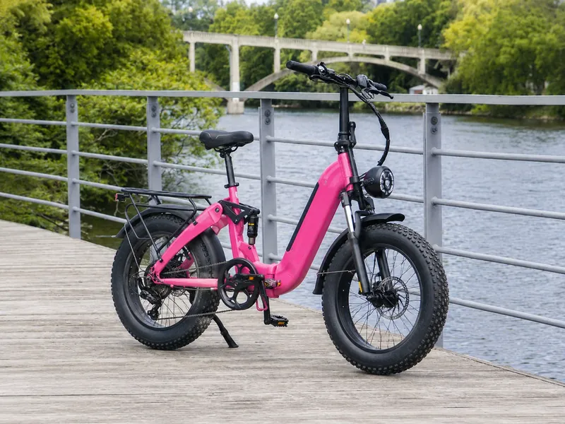 Pink folding fat-tire electric bike on a wooden boardwalk by a river